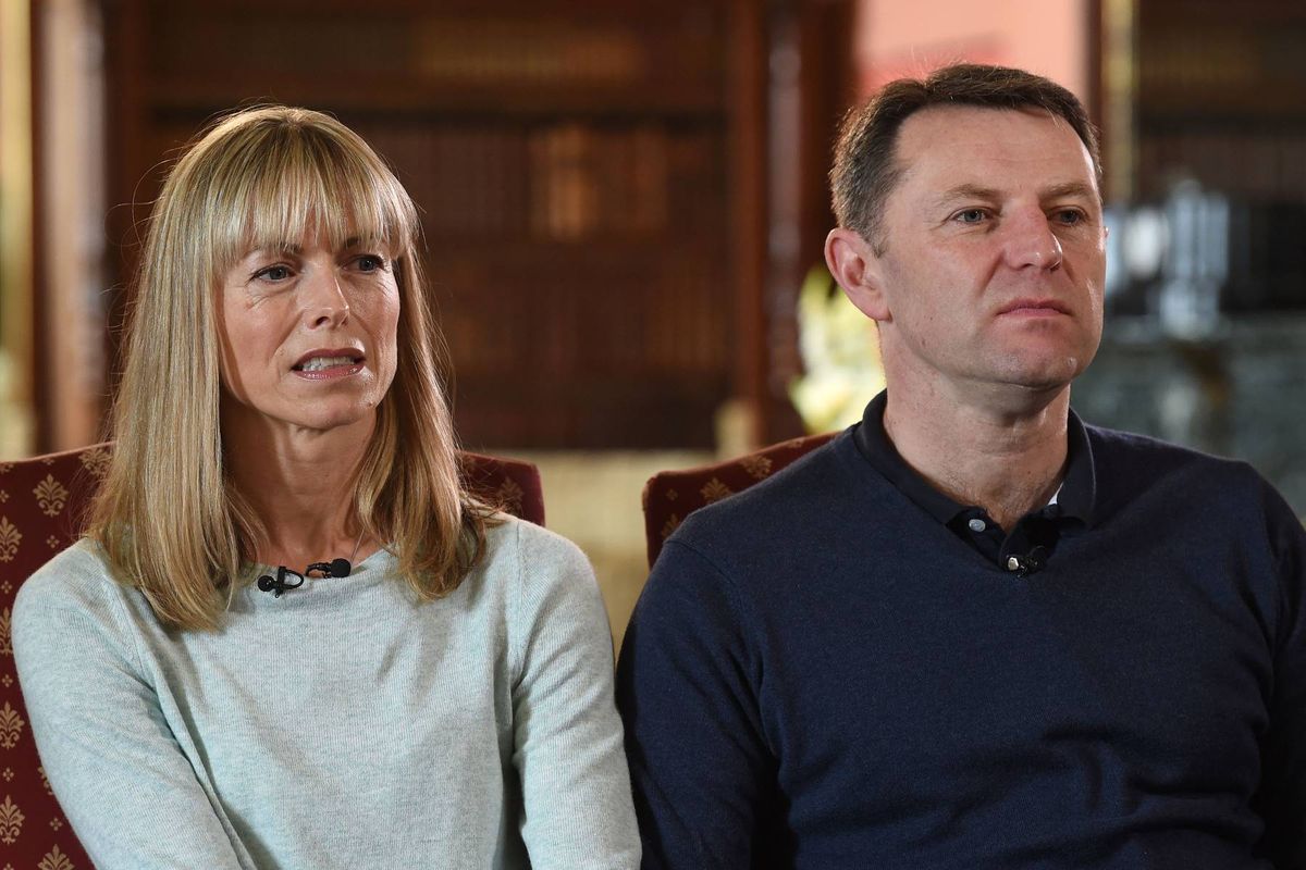 An adult man and woman seated closely together on a chair, both appearing to be engaged in a serious conversation, with a slightly blurred background that suggests an indoor setting.